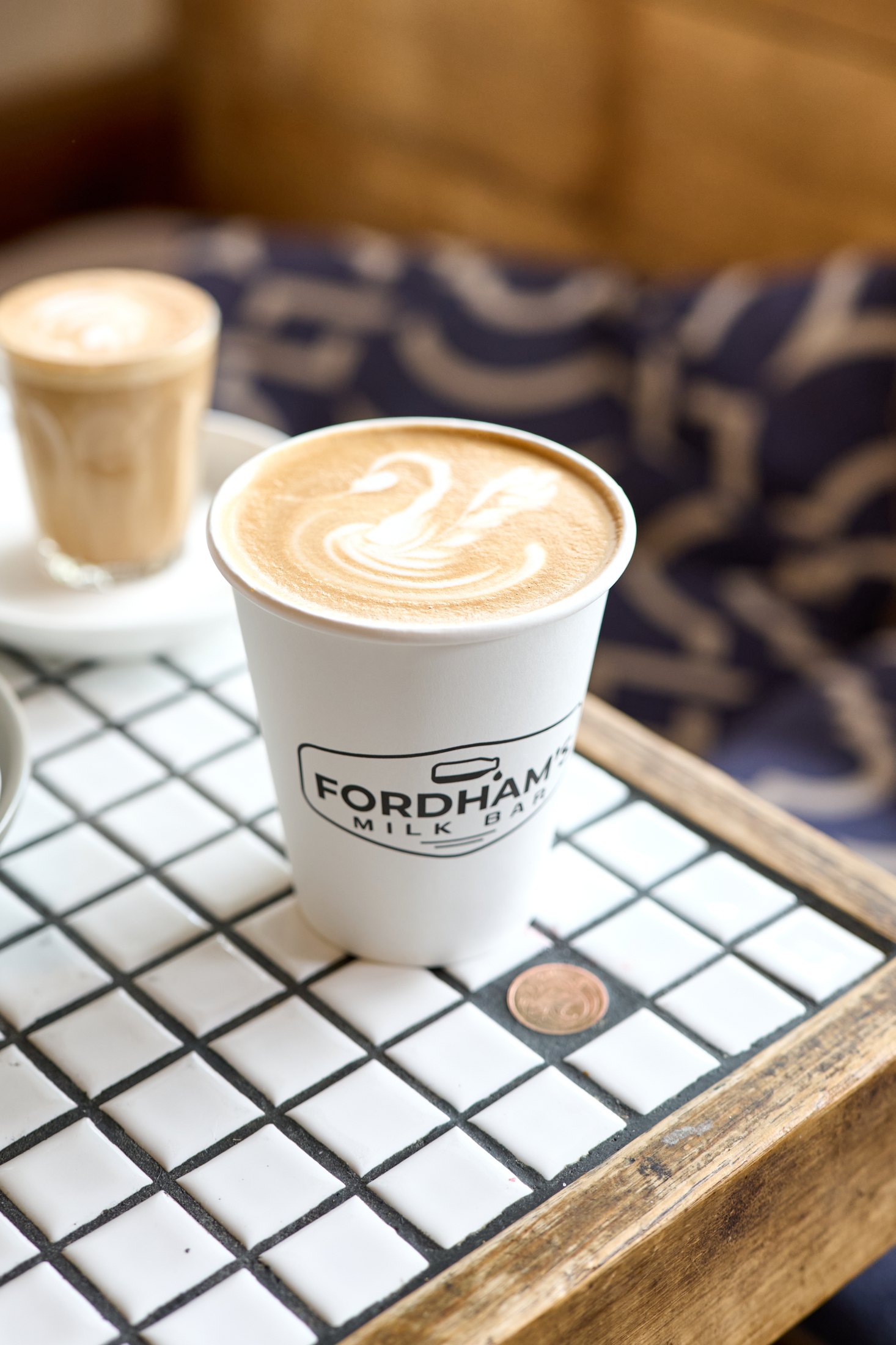 Fordham’s branded coffee cup on a tiled café table