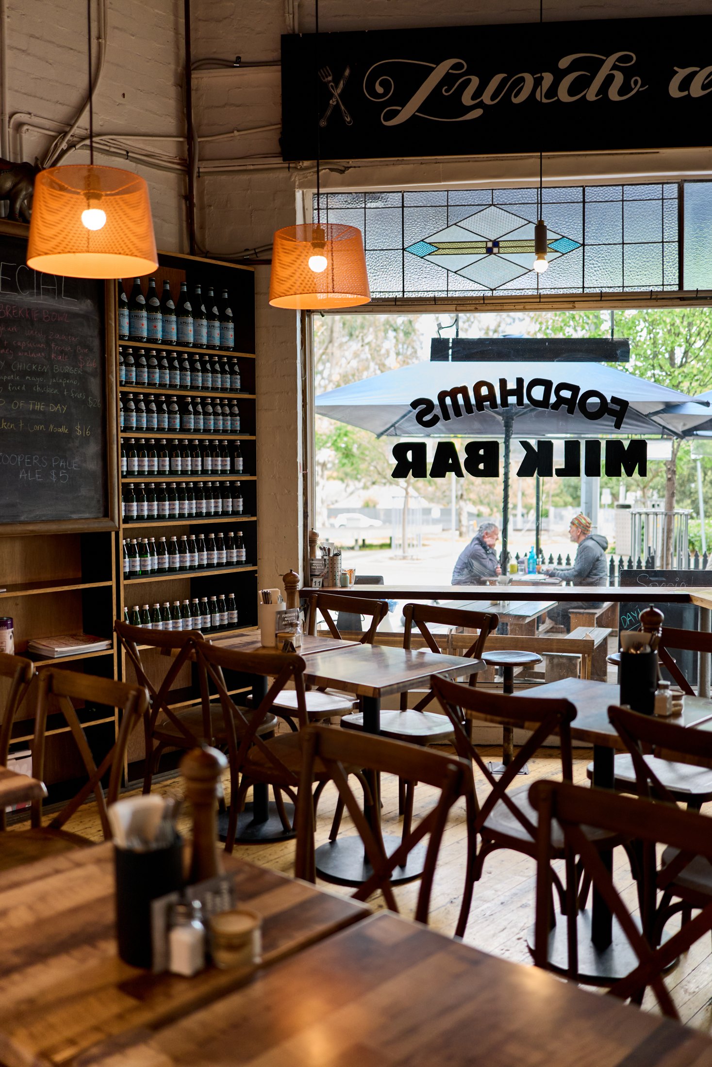 Warm timber tables and window light inside Fordham’s Milk Bar